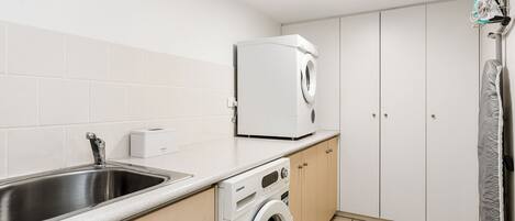A compact kitchen with a stainless steel sink, a built-in washing machine, and a microwave.