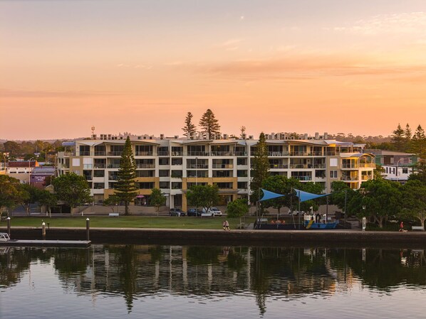 A multi-story building with balconies, a dock, and a reflection in the water. - Riverside Apartments & Hotel Ballina (Ballina)