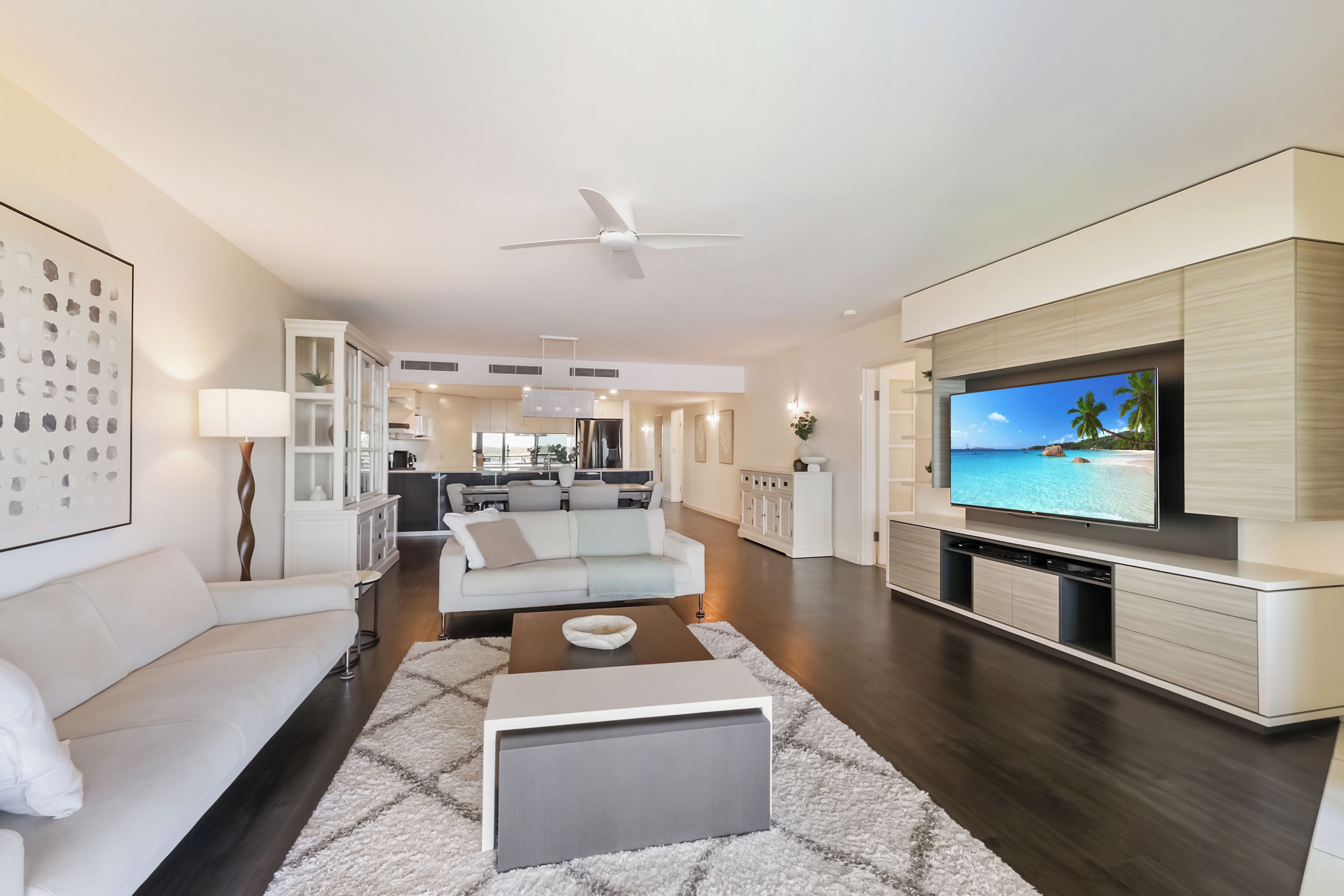 A modern living room with a sofa, coffee table, TV, and a ceiling fan.