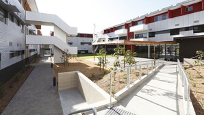 A modern building with a central courtyard, outdoor seating area, and a staircase leading to an upper level. - Western Sydney University Village- Parramatta Campus (Parramatta)