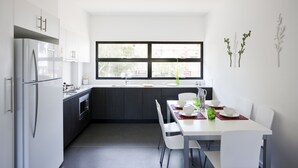 A modern kitchen with a dining area, featuring a large window, white cabinetry, and a minimalist design. - Western Sydney University Village- Parramatta Campus (Parramatta)