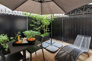 A patio with a table set for breakfast, including a tray with toast, fruit, and a beverage. - Platine Hotel (Paris)