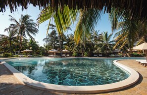 A swimming pool with clear water, surrounded by palm trees and lounge chairs. - Ocean Beach Resort & Spa (Malindi)