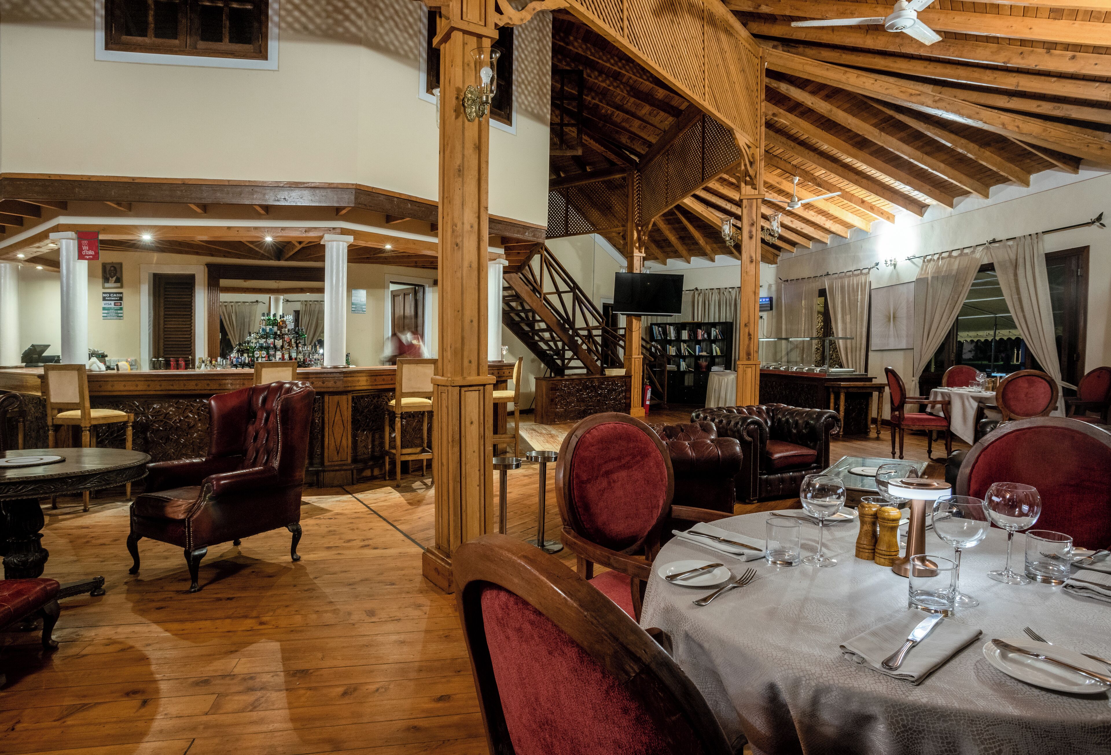 Un restaurante con vigas de madera, sillas de cuero y una zona de bar.