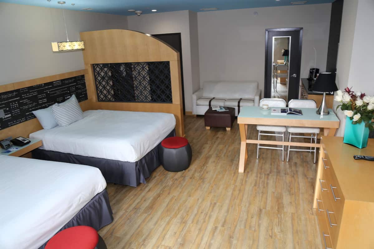 Ein Hotelzimmer mit zwei Betten, einem Schreibtisch, einem Stuhl, einem Spiegel und einem kleinen Tisch.