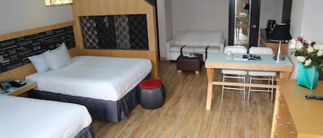 A hotel room with two beds, a desk, a chair, a mirror, and a small table.