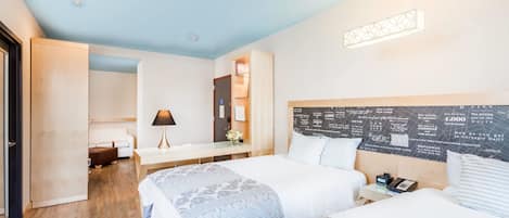 A hotel room with two beds, a desk, a chair, a nightstand, and a wall with text.