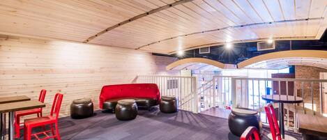 A modern interior with wooden walls, a red sofa, and a bar area with stools.