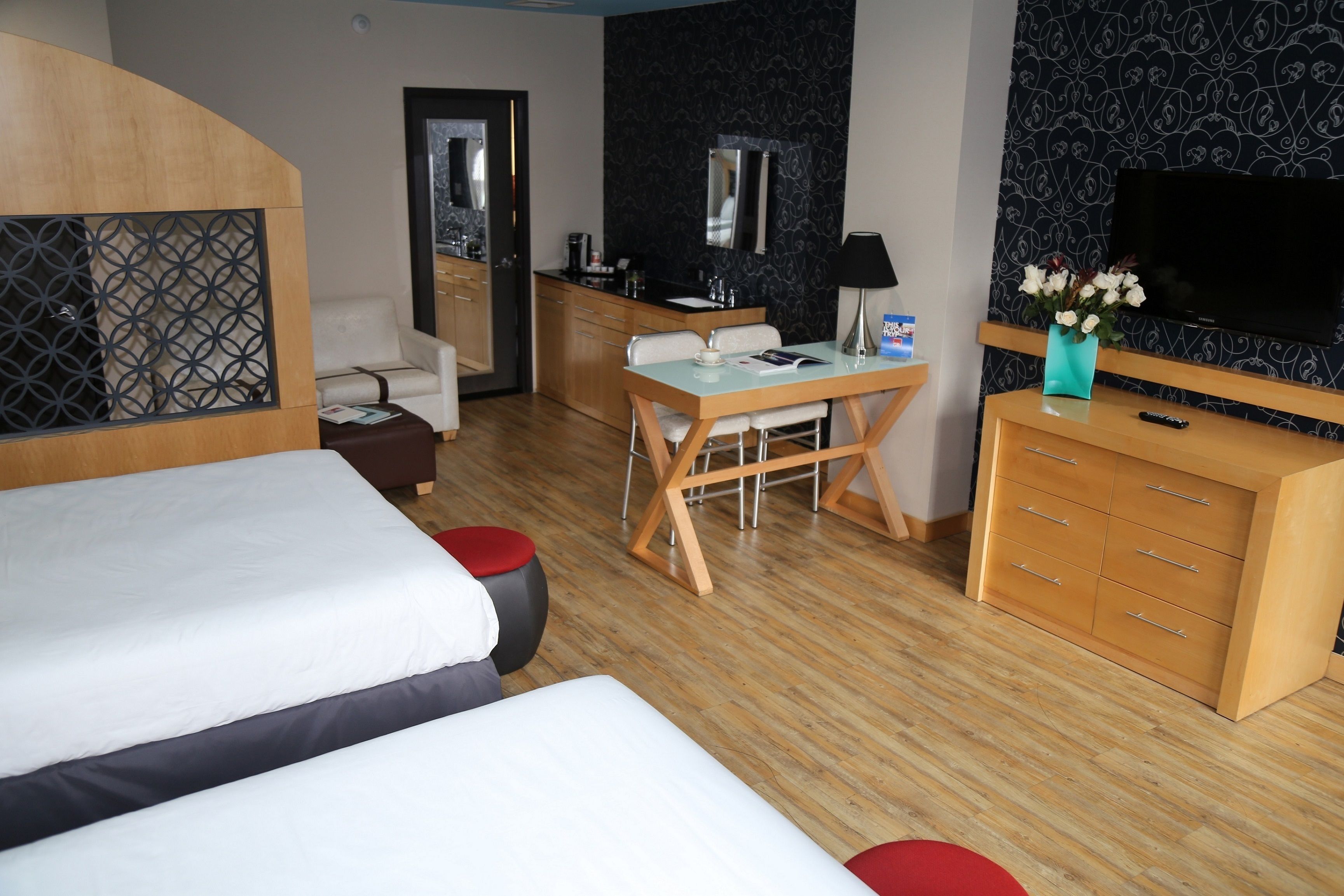 Quarto de hotel com duas camas, uma escrivaninha, televisão e minibar.