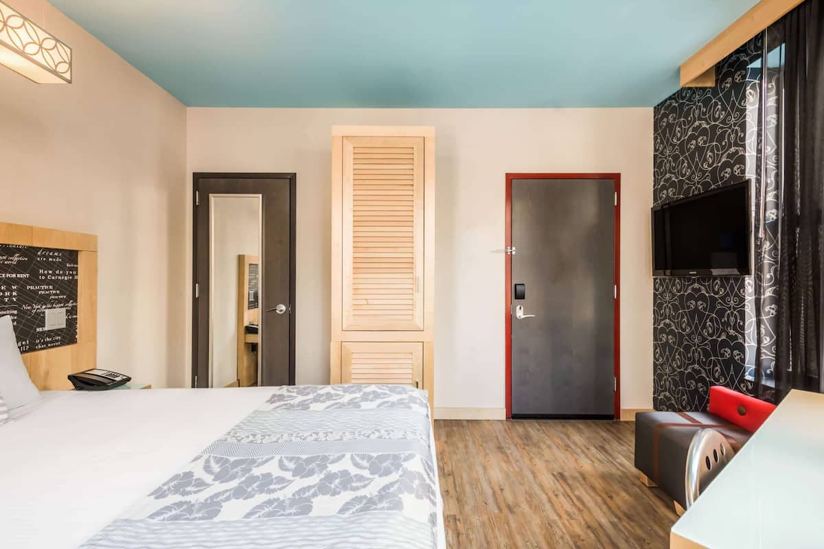 Ein Hotelzimmer mit Bett, Schreibtisch, Fernseher und Kleiderschrank.