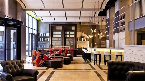 A modern lounge area with leather sofas, a bar area, and a seating area with a patterned rug. - TRYP by Wyndham New York City Times Square / Midtown (New York)