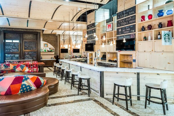 A cozy bar area with a wooden ceiling, a counter with stools, and shelves with various items. - TRYP by Wyndham New York City Times Square / Midtown (New York)