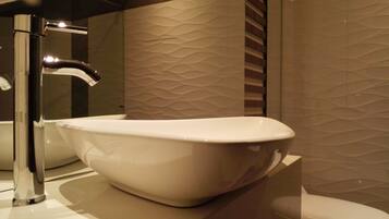 Ein modernes Badezimmer mit einer weißen, freistehenden Badewanne, einem Chromarmaturenset und einer strukturierten Wand.