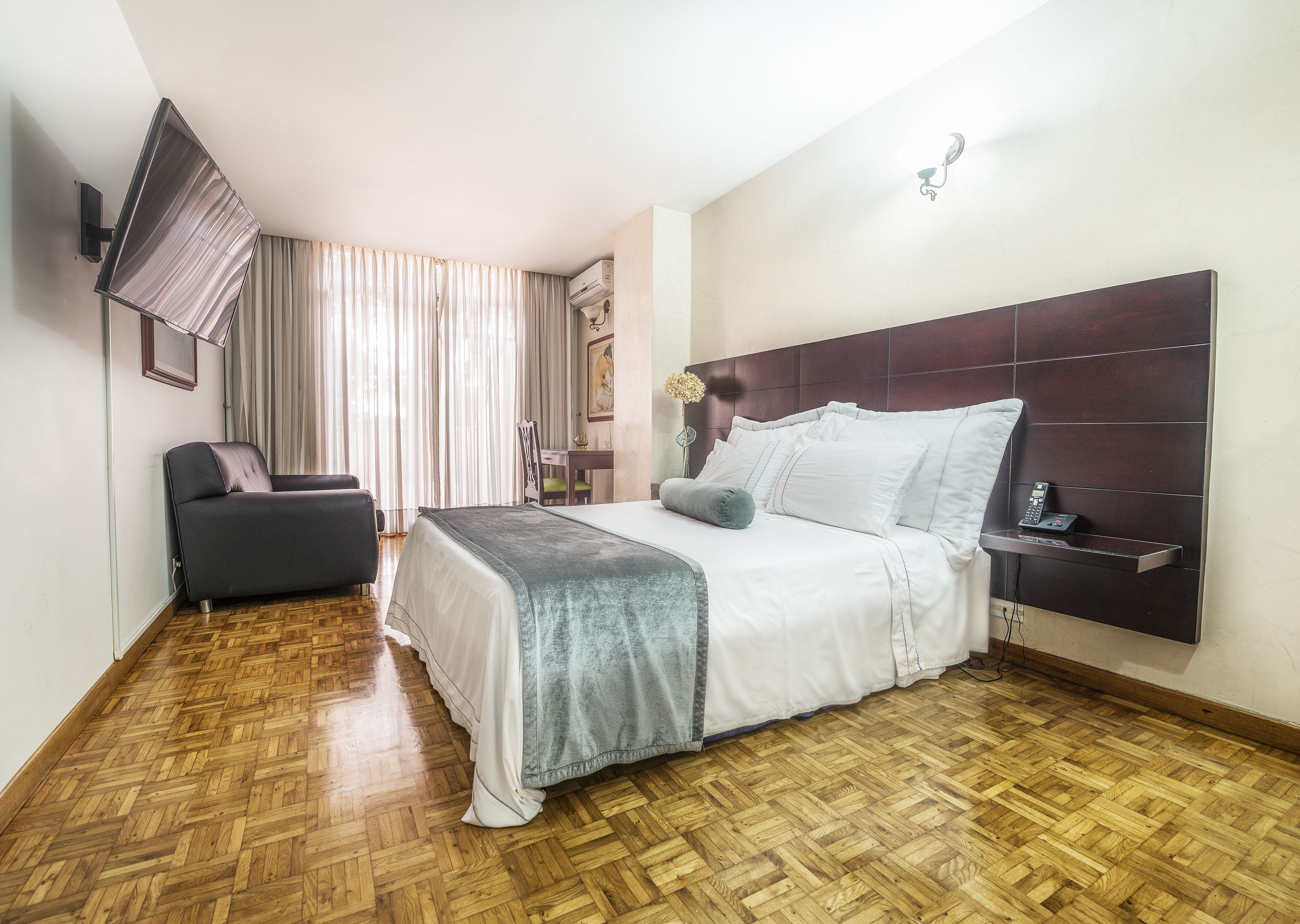 Una habitación de hotel con cama, escritorio, silla y televisor.