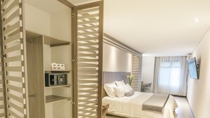 Una habitación de hotel moderna con una cama grande, un escritorio y un vestidor.