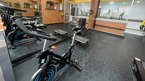 Un gimnasio con equipo de ejercicio, una pared de ladrillo y una ventana con plantas.