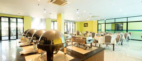A buffet setup with multiple serving stations, a clean and modern interior, and large windows providing natural light.