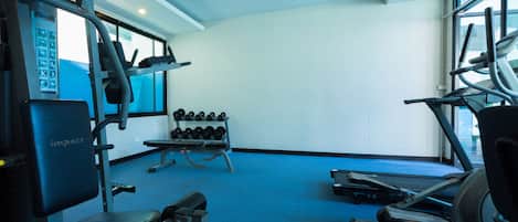 A gym with exercise equipment, a rack of dumbbells, and a blue carpet.