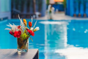 Un vase en verre avec des fleurs, posé sur une table au bord de la piscine.