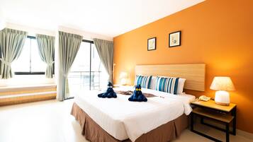 A hotel room with a large bed, two pillows, a bedside table with a lamp, and a window with curtains.