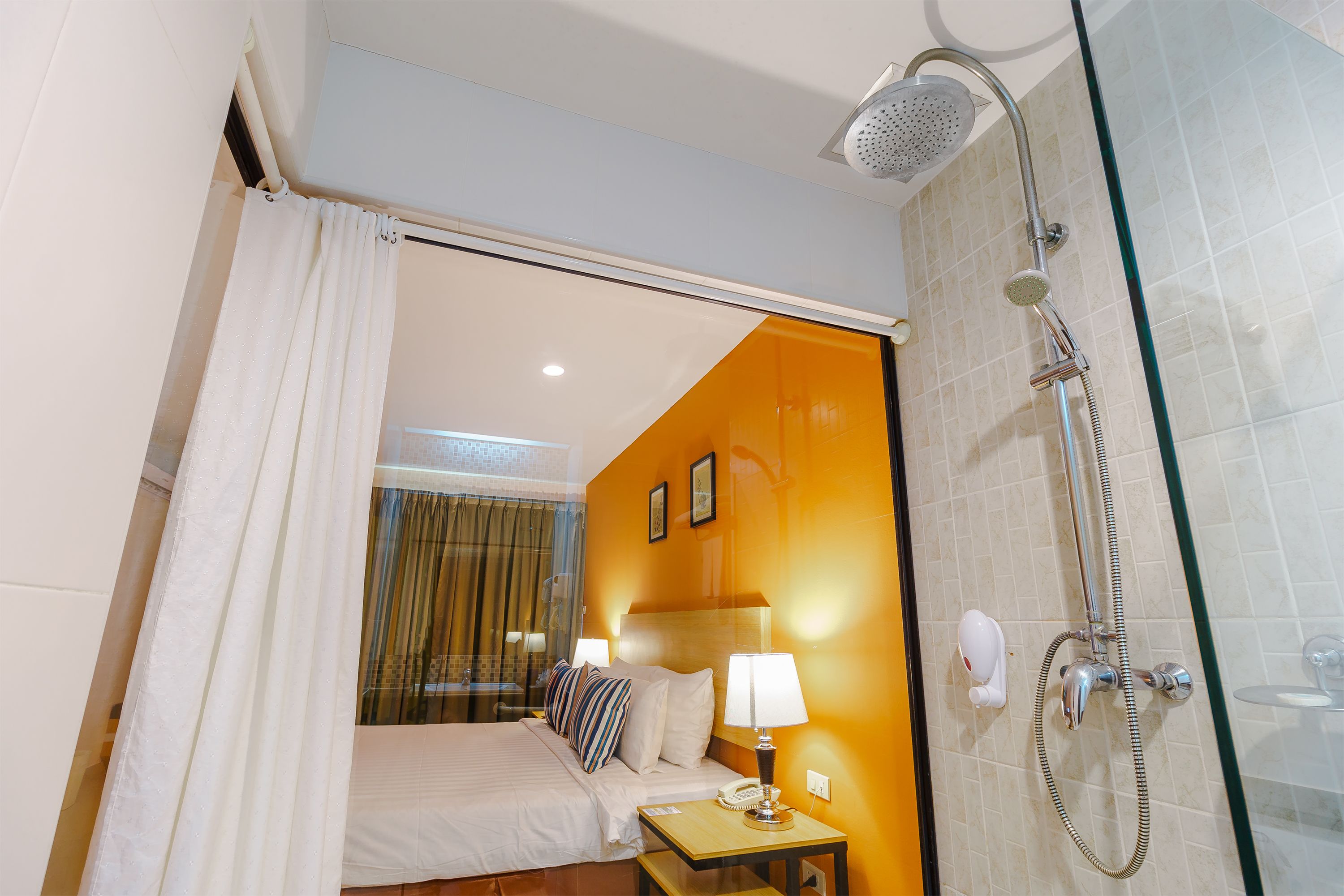 Une chambre d’hôtel équipée d’un lit, d’une table de chevet, d’une lampe et d’un espace douche.