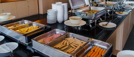 A buffet with various food options including hot dogs, carrots, and other dishes.