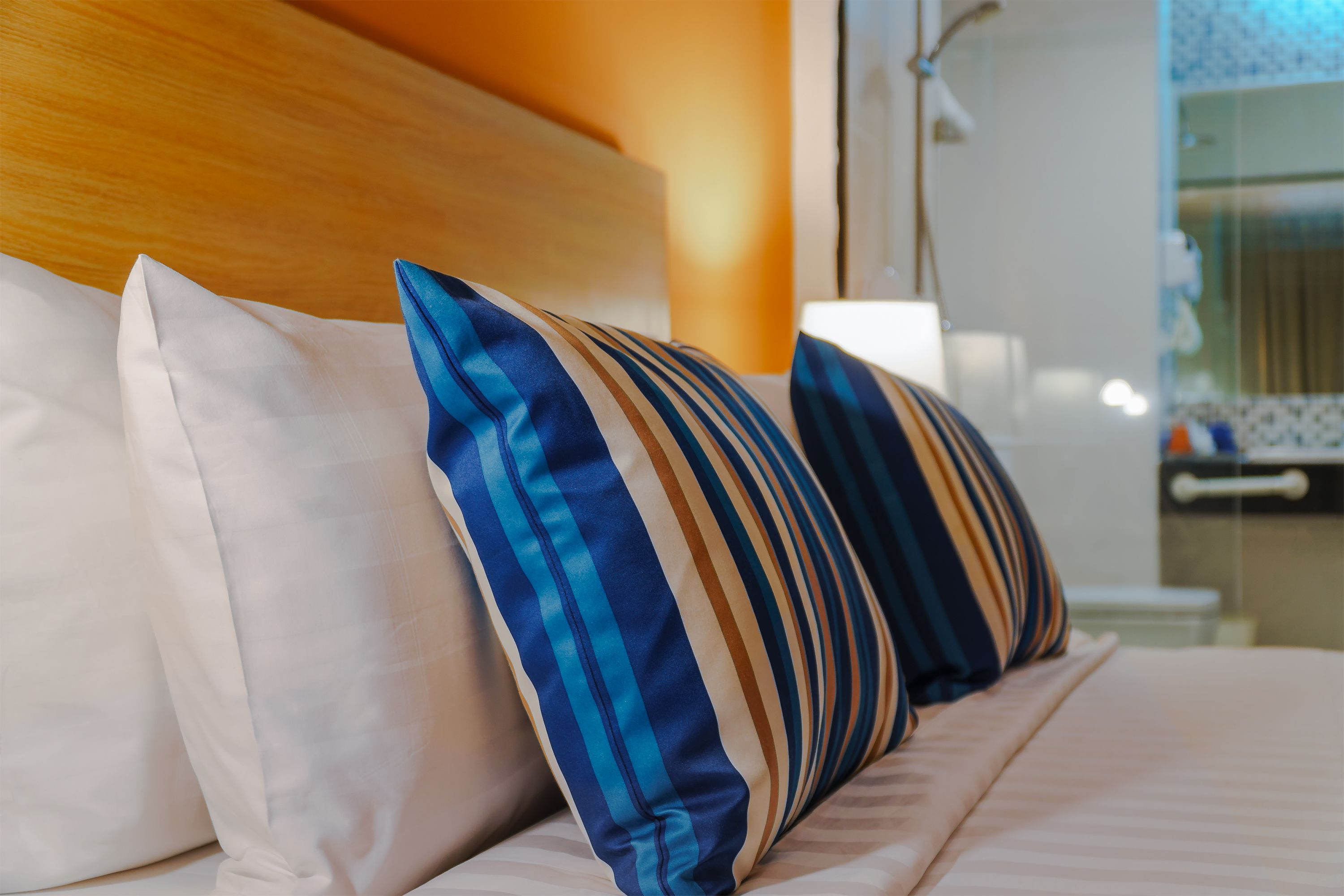 A bed with striped pillows and a wooden headboard.