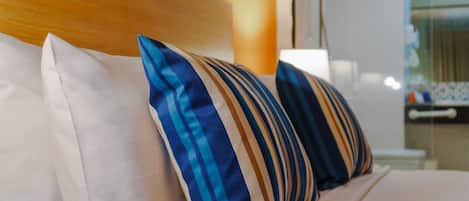 Una cama con almohadillas a rayas y un cabecero de madera.