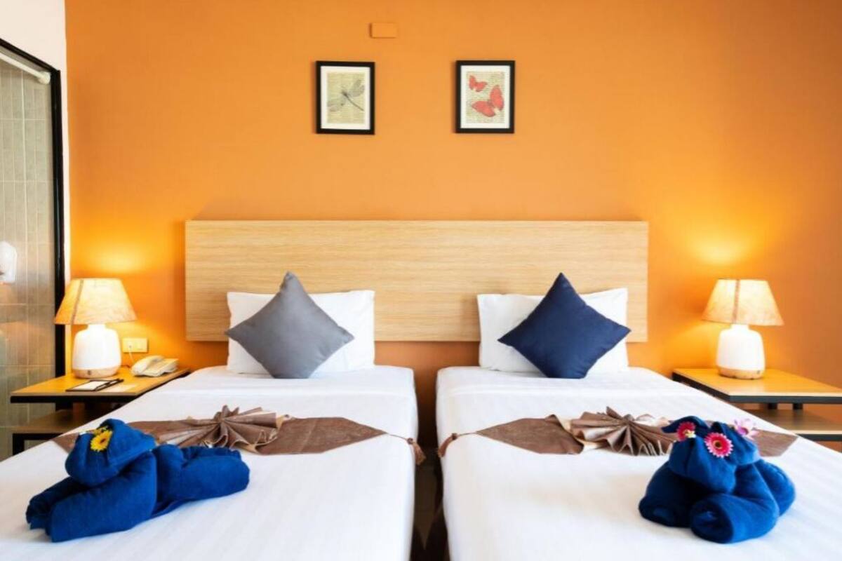 A hotel room with two beds, each with a pillow, a nightstand, a lamp, and a framed picture on the wall.