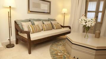 A modern living room with a sofa, two floor lamps, a vase with flowers, and a patterned rug.