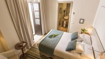 A hotel room with a bed, a bedside table, a lamp, and a view of the bathroom.