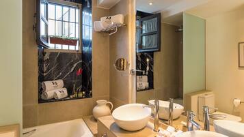 A modern bathroom with a large mirror, a bathtub, a sink, and a shower area.
