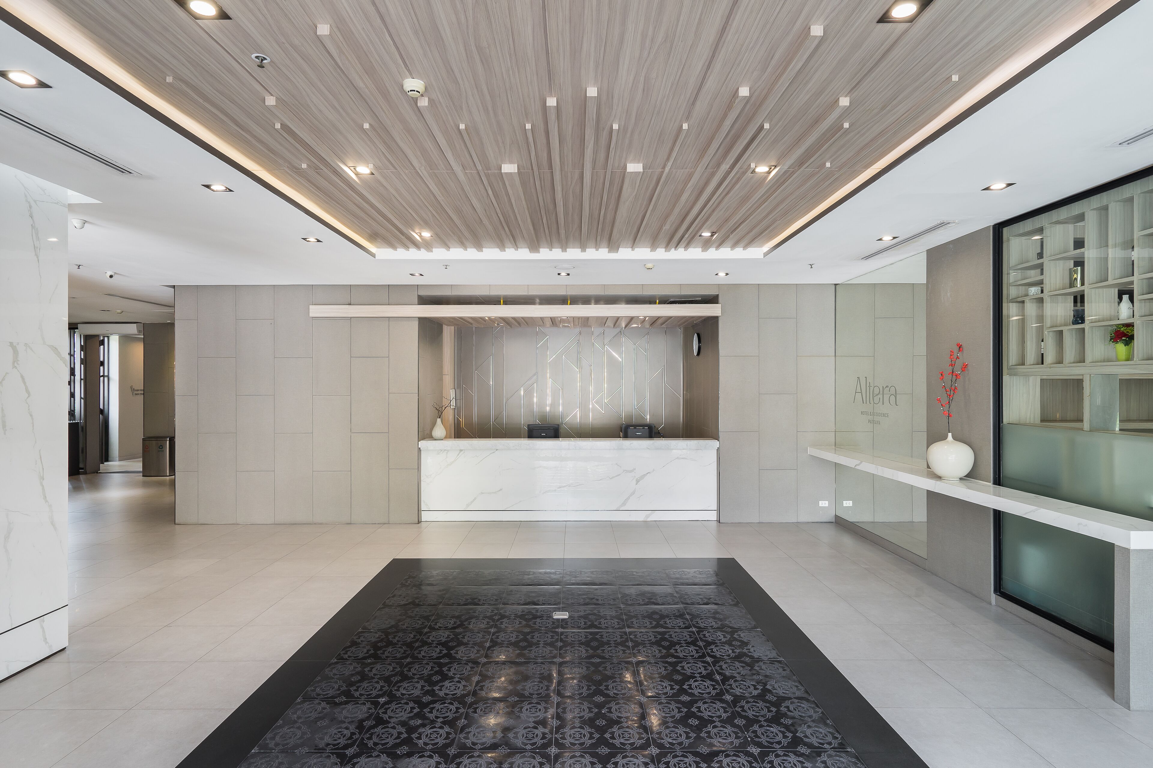 A modern reception area with a marble reception desk, a patterned carpet, and a glass display cabinet.