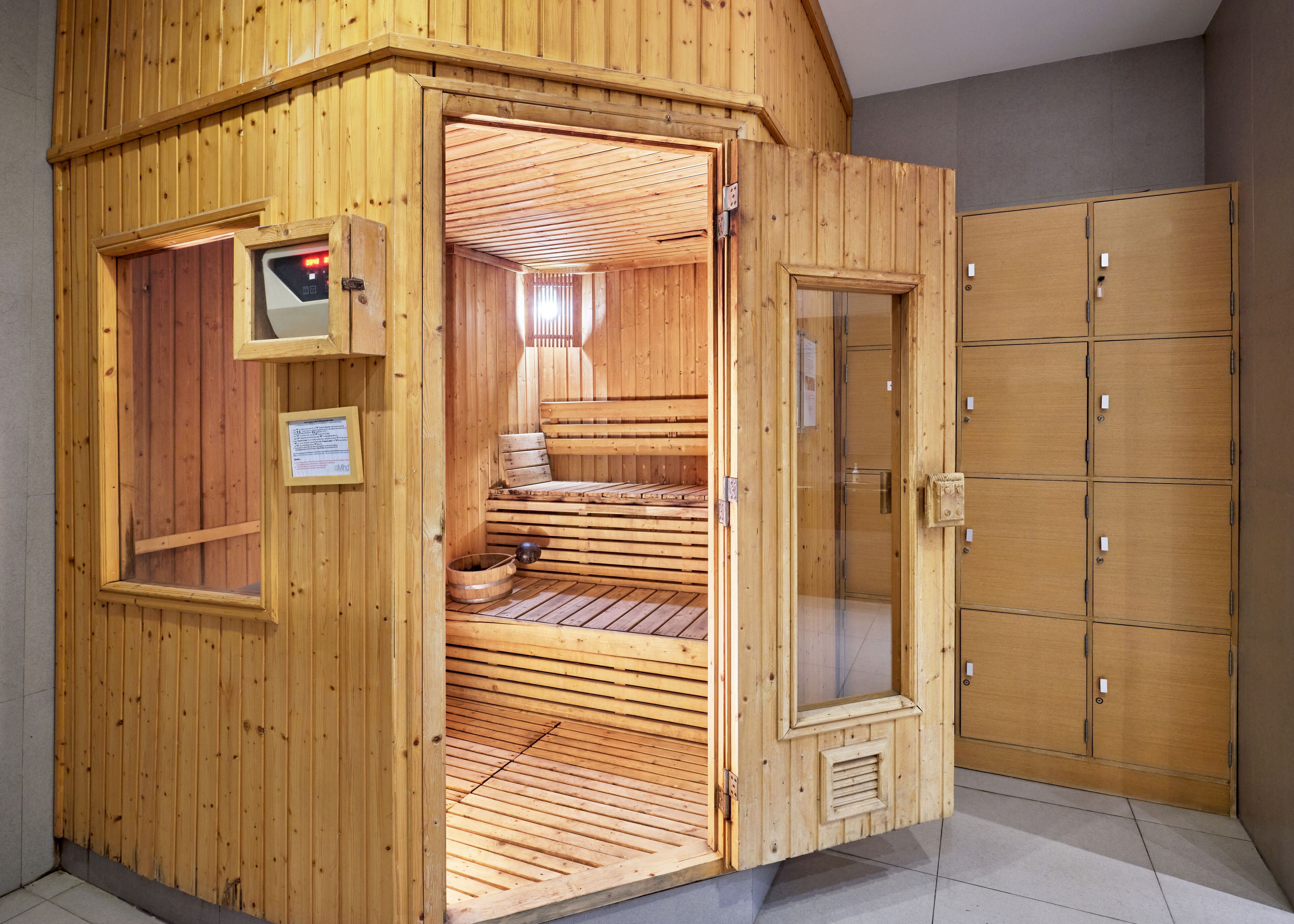 A wooden sauna with a glass door, wooden benches, and a small window.
