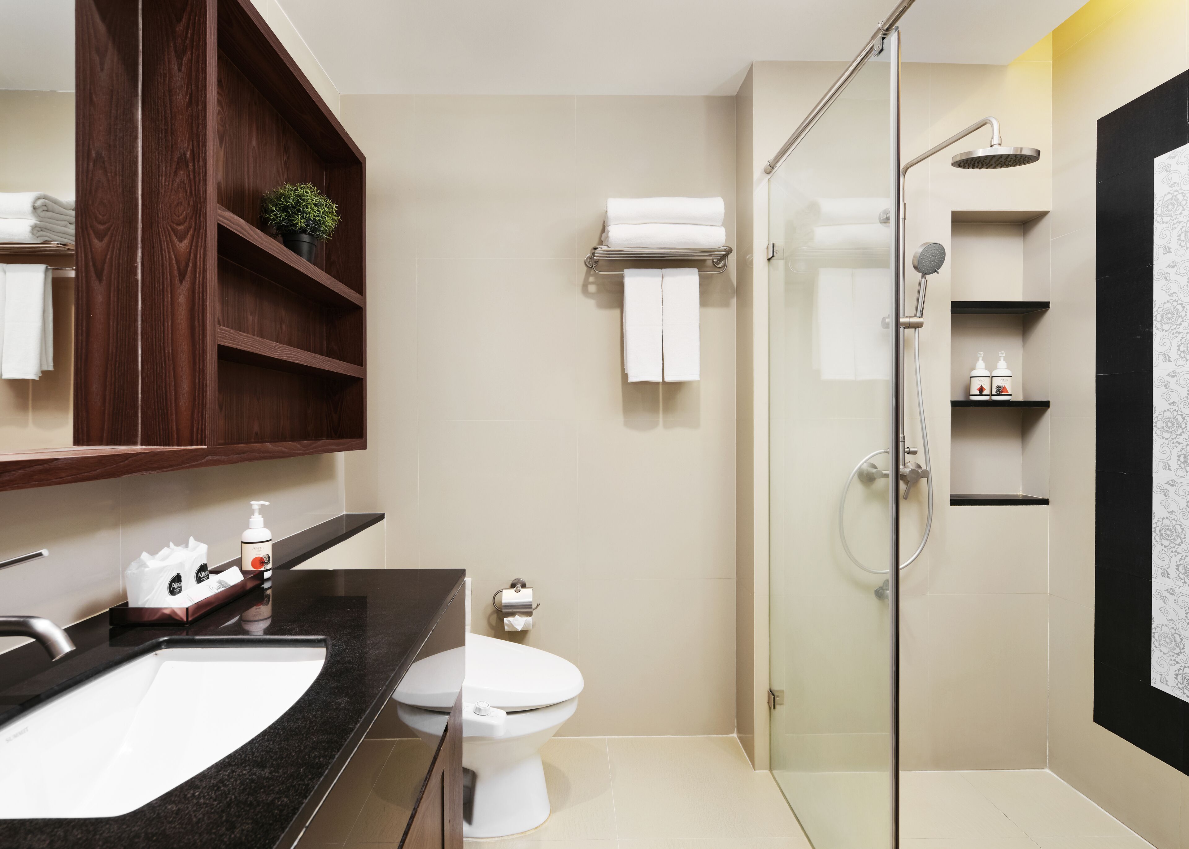 A modern bathroom with a glass-enclosed shower, a white toilet, and a black countertop with a sink.