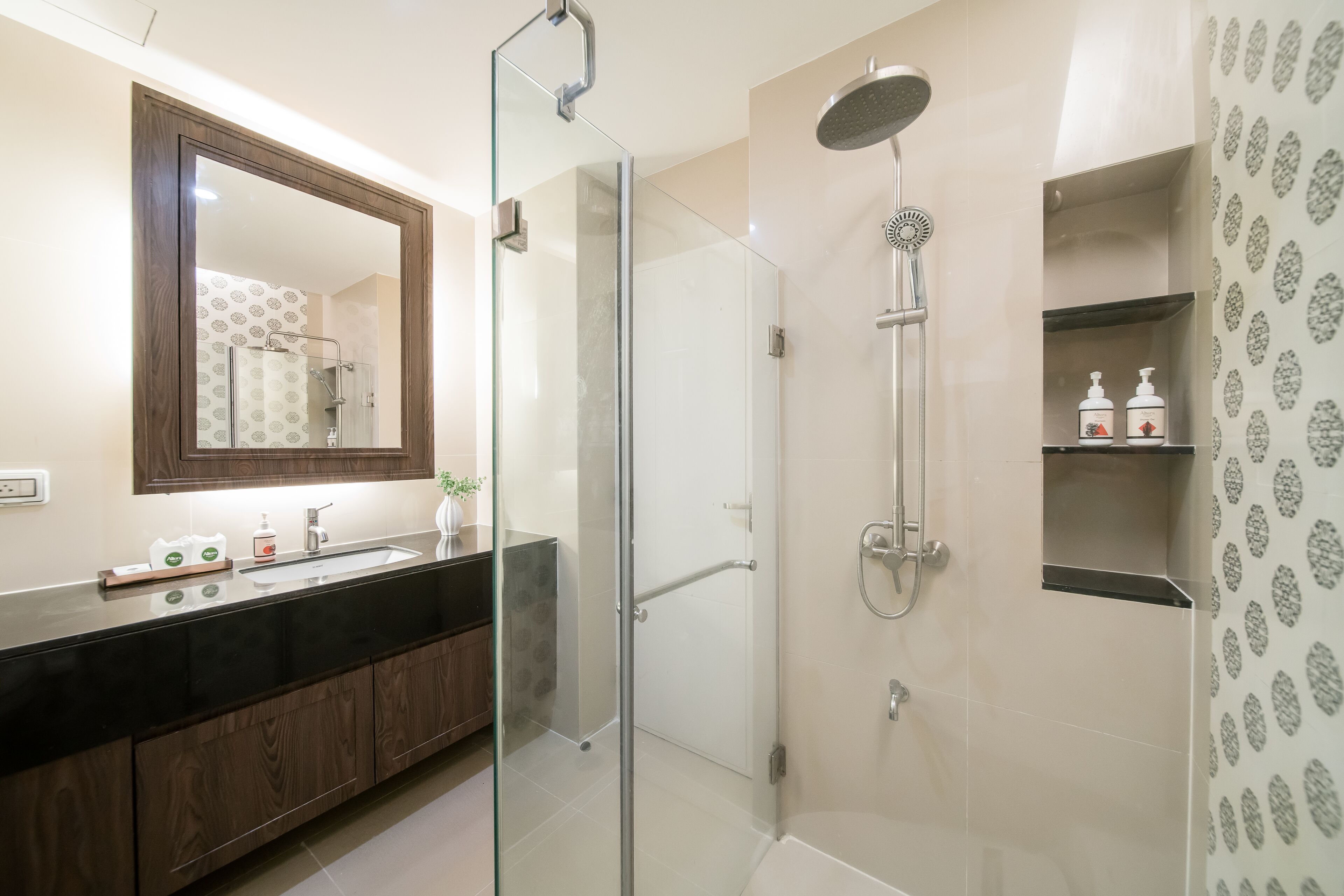 Un baño moderno con ducha de vidrio, un espejo grande y encimera negra.