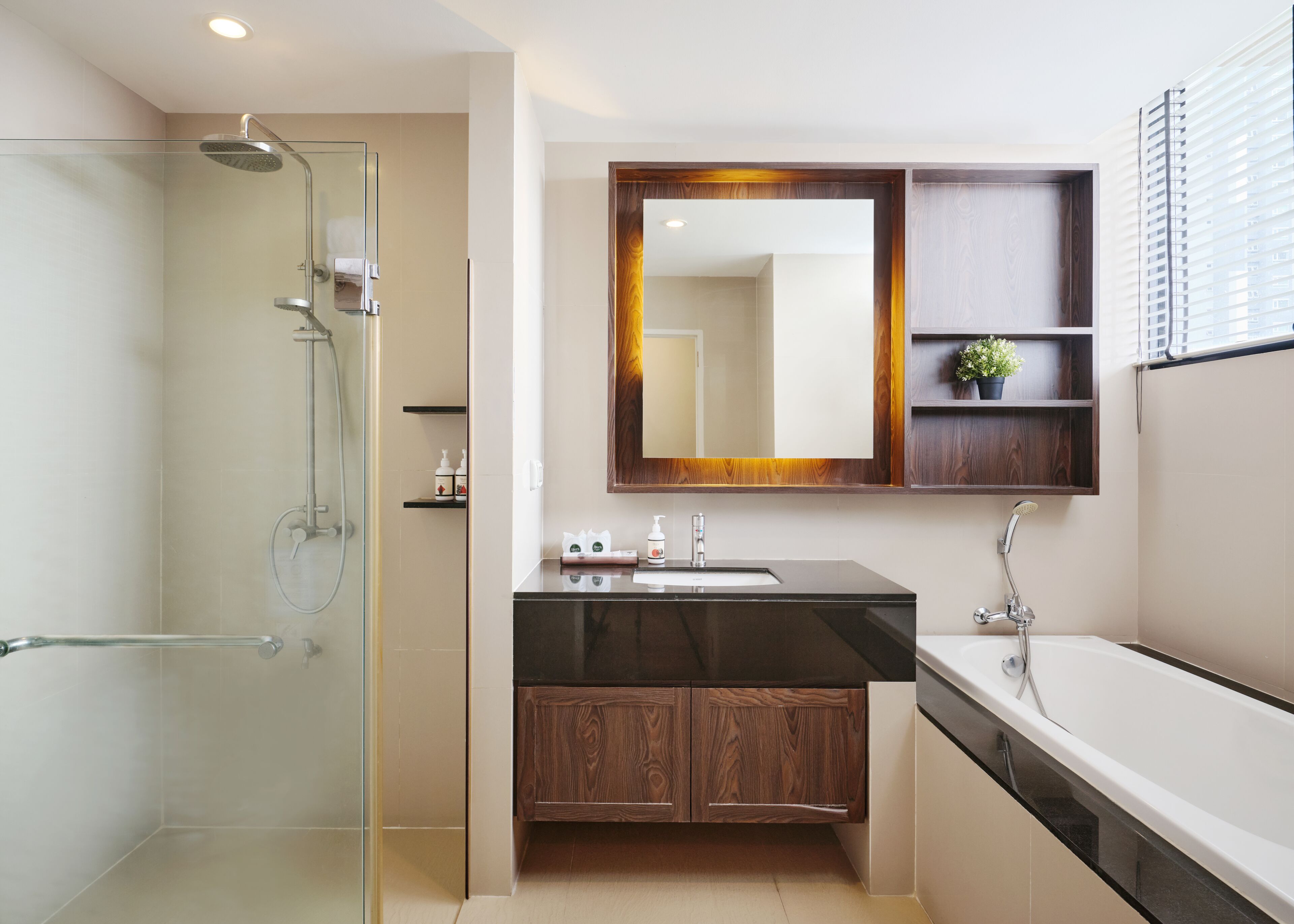 A modern bathroom with a glass shower enclosure, a wooden vanity, and a large mirror above the sink.