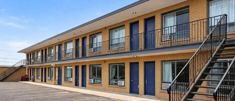 Un motel à deux étages, doté d’un parking, de nombreuses chambres et d’un escalier.