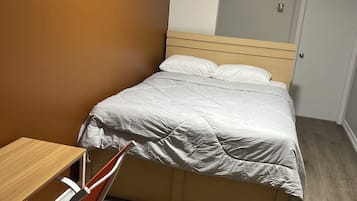A bedroom with a bed, a wooden desk, and a chair.