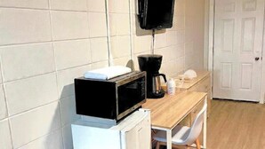 A compact kitchen area with a microwave, coffee maker, and a small refrigerator. -  Inn On Pim (Sault Ste. Marie)