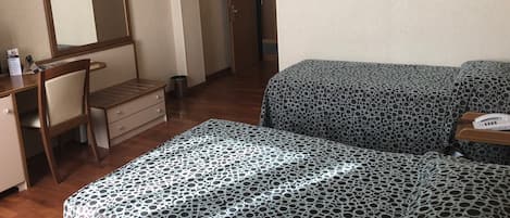 A hotel room with a bed, a desk, a chair, and a mirror.