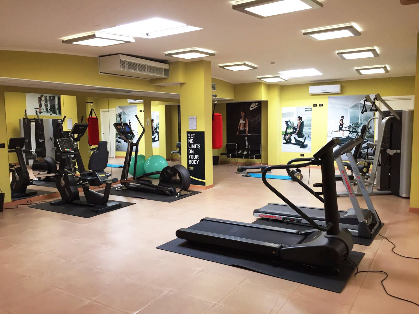 A gym with various exercise equipment, including treadmills and weight machines, and motivational posters on the walls.