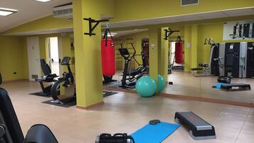 Un gimnasio con equipo de ejercicio, un saco de boxeo y una colchoneta azul.