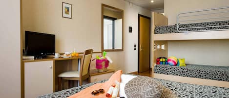 Habitación de hotel con literas, un escritorio con computadora, una silla y una pequeña mesa con artículos para el desayuno.