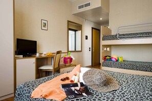 Habitación de hotel con literas, un escritorio con computadora, una silla y una pequeña mesa con artículos para el desayuno.