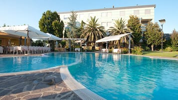 Una piscina al aire libre, sombrillas, sillones reclinables de piscina