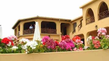 A building with multiple balconies and a flower garden in front.