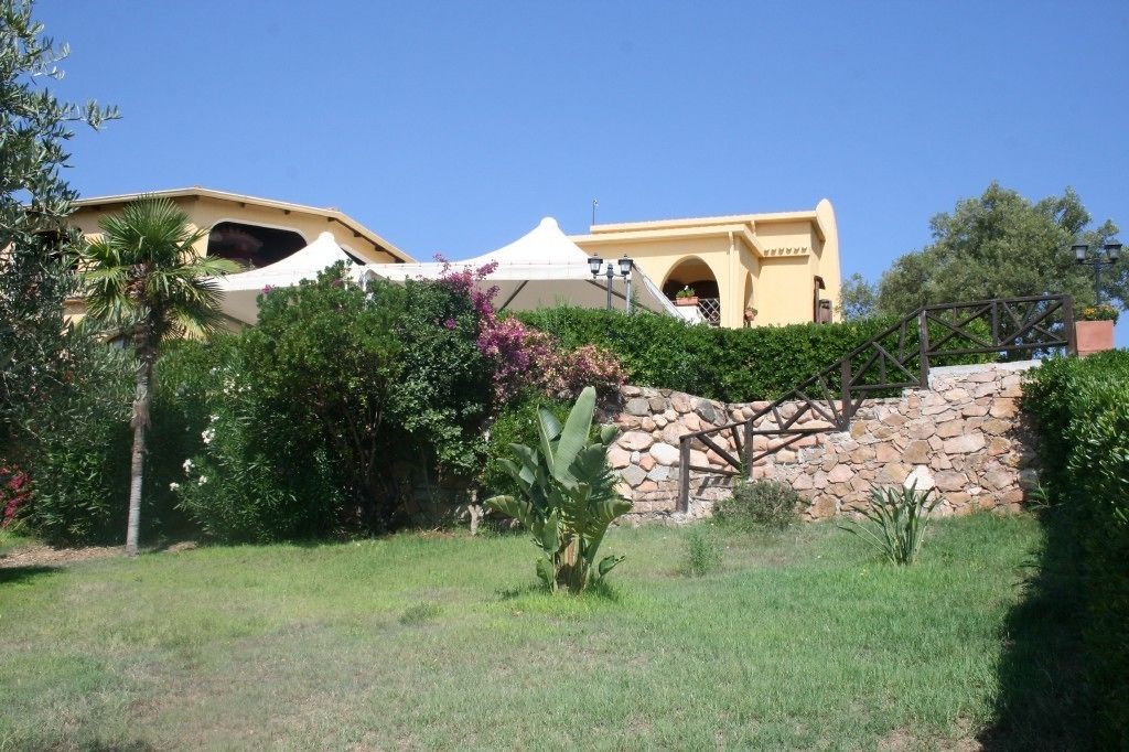 A building with a stone wall and a wooden staircase leading to a door.