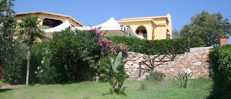 A building with a stone wall and a wooden staircase leading to a door.