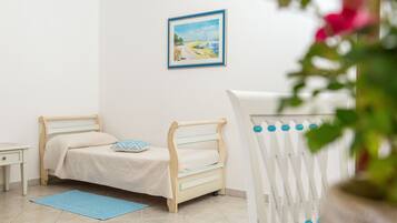 Une chambre d’enfant avec un lit, une table de chevet, un tapis bleu et un tableau accroché au mur.
